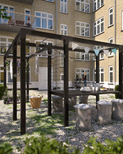 Daylife Pergola Modell 4 mit Tisch, Trockengestell, Fitnessmodul und Spalier in einem Innenhof mit Sitzbereich und Wäscheleine.
