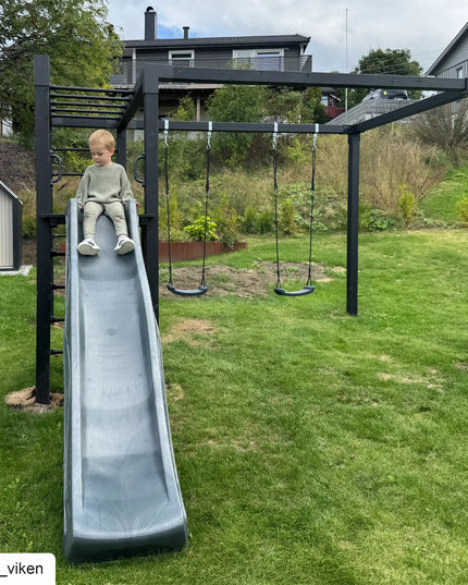 PLUS Daylife Schaukel 3 in einem Garten mit einem Bub auf der Rutsche
