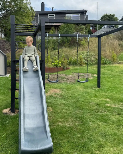 Kind rutscht auf einer PLUS Daylife Schaukel 3 in einem Garten