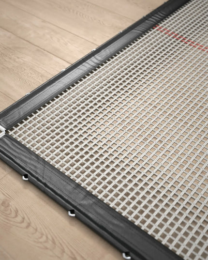 Detailansicht der ACON X Wettkampf-Trampolinmatte mit weißem Gittergewebe, schwarzer Randverstärkung und Befestigungsöse.