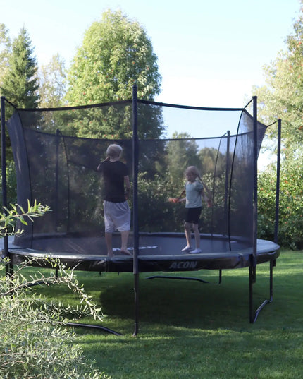 ACON AIR Gen 2.0 Rundtrampolin mit Sicherheitsnetz, auf dem zwei Kinder in einem grünen Garten spielen.