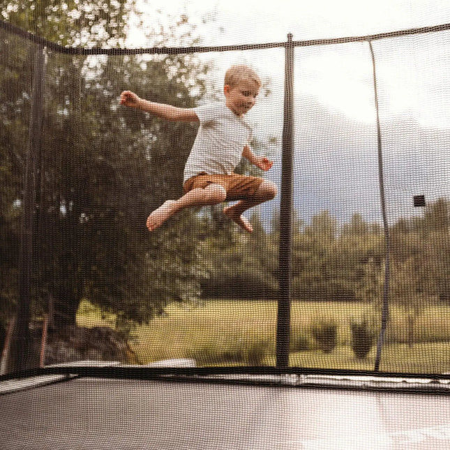 Kind springt auf einem ACON HD Trampolin mit umlaufendem Sicherheitsnetz im Garten.